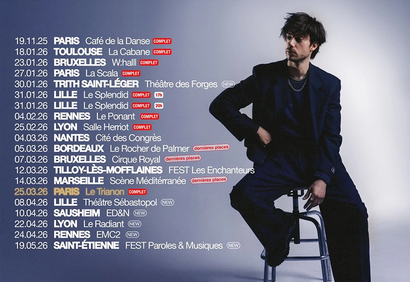 Félix Radu assis sur un tabouret haut à coté de la liste des dates de la tournée 2026